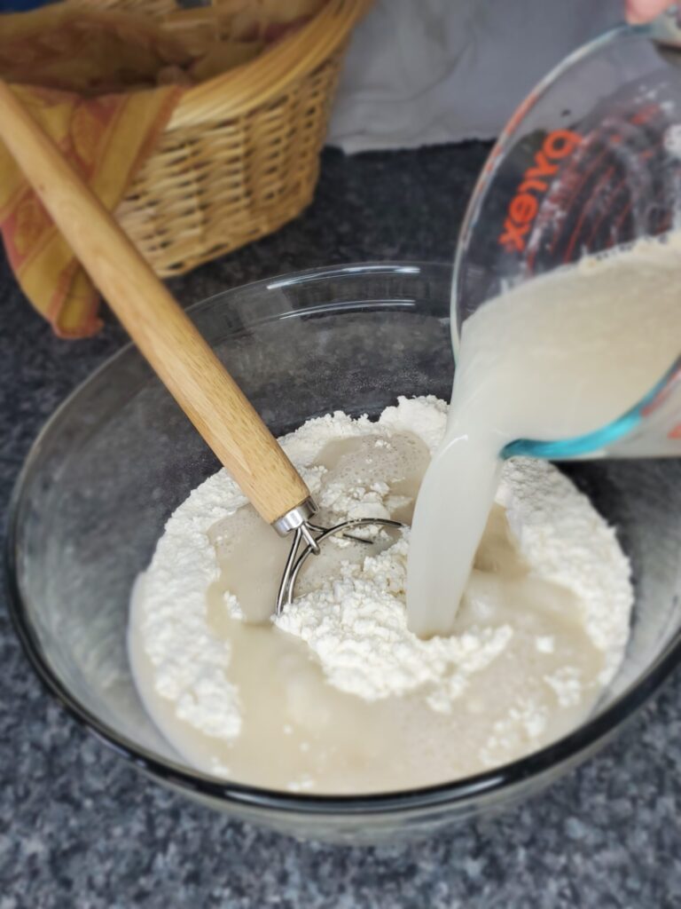 Adding yeast, water, and sugar to flour and salt mixture