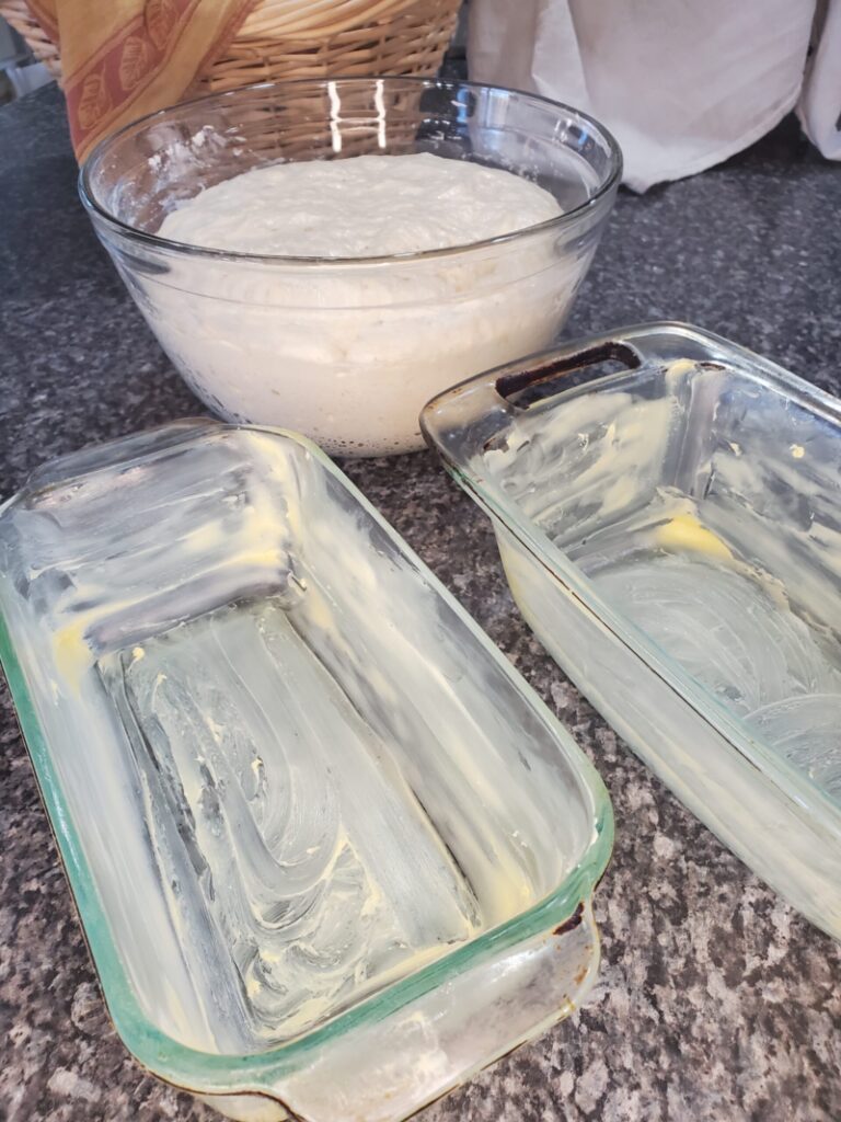 two bread pans greased with butter